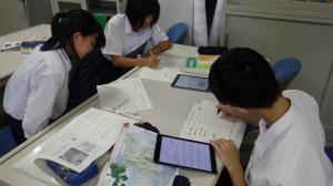 学校でタブレットを使って学習する三人の生徒
