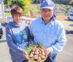 GAP評価を受けて生産したしいたけを持つ生産者夫婦