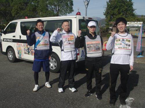 移動交番の前でポーズをとる選手